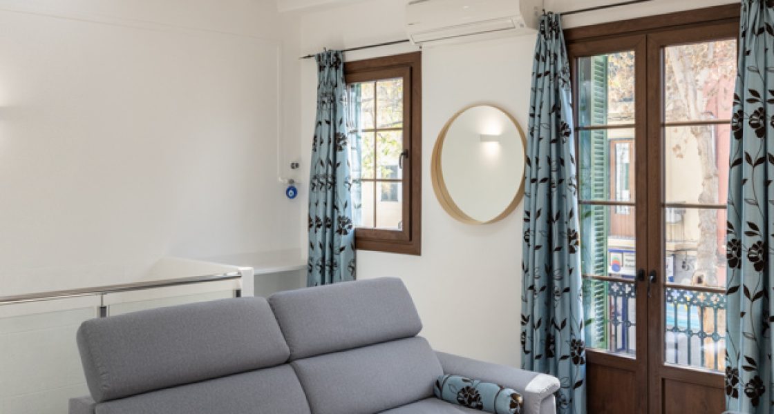 Elegant grey sofa next to blue curtains with brown flower details
